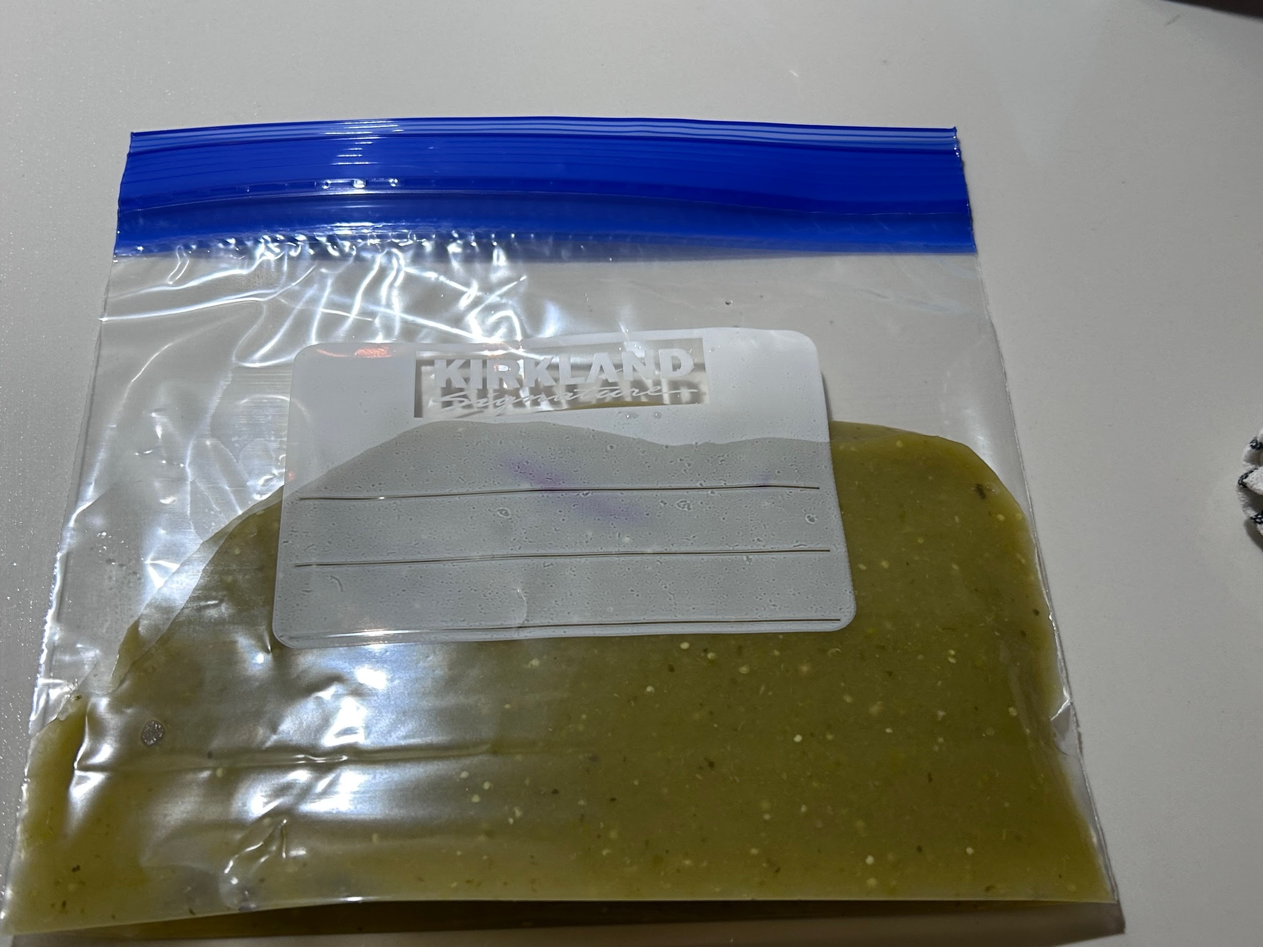 A Kirkland freezer bag filled flat with green sauce